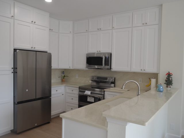 Freshly installed white kitchen cabinetry with light quartz countertops