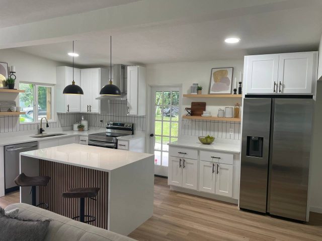 White custom kitchen cabinetry with a wood-slat island and pendant lighting